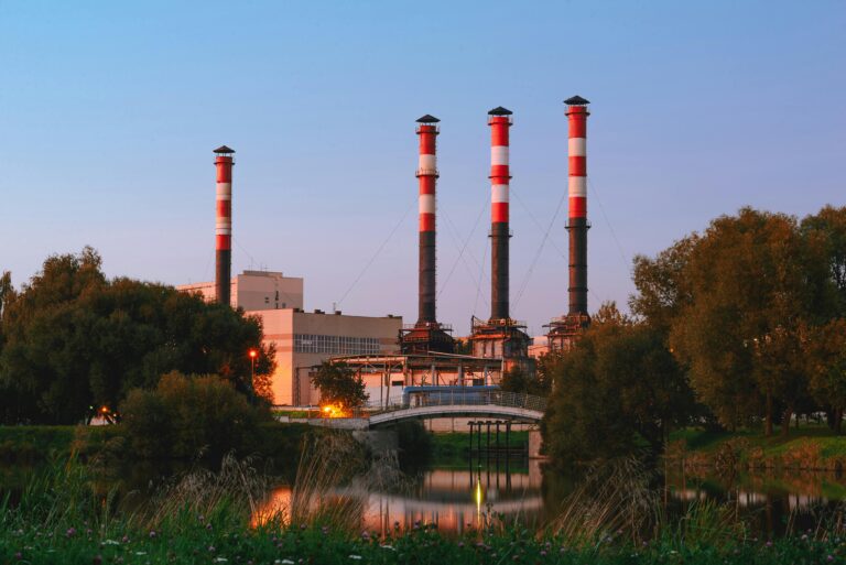 View of an industrial plant with tall chimneys by a lake in Minsk, Belarus during the day.